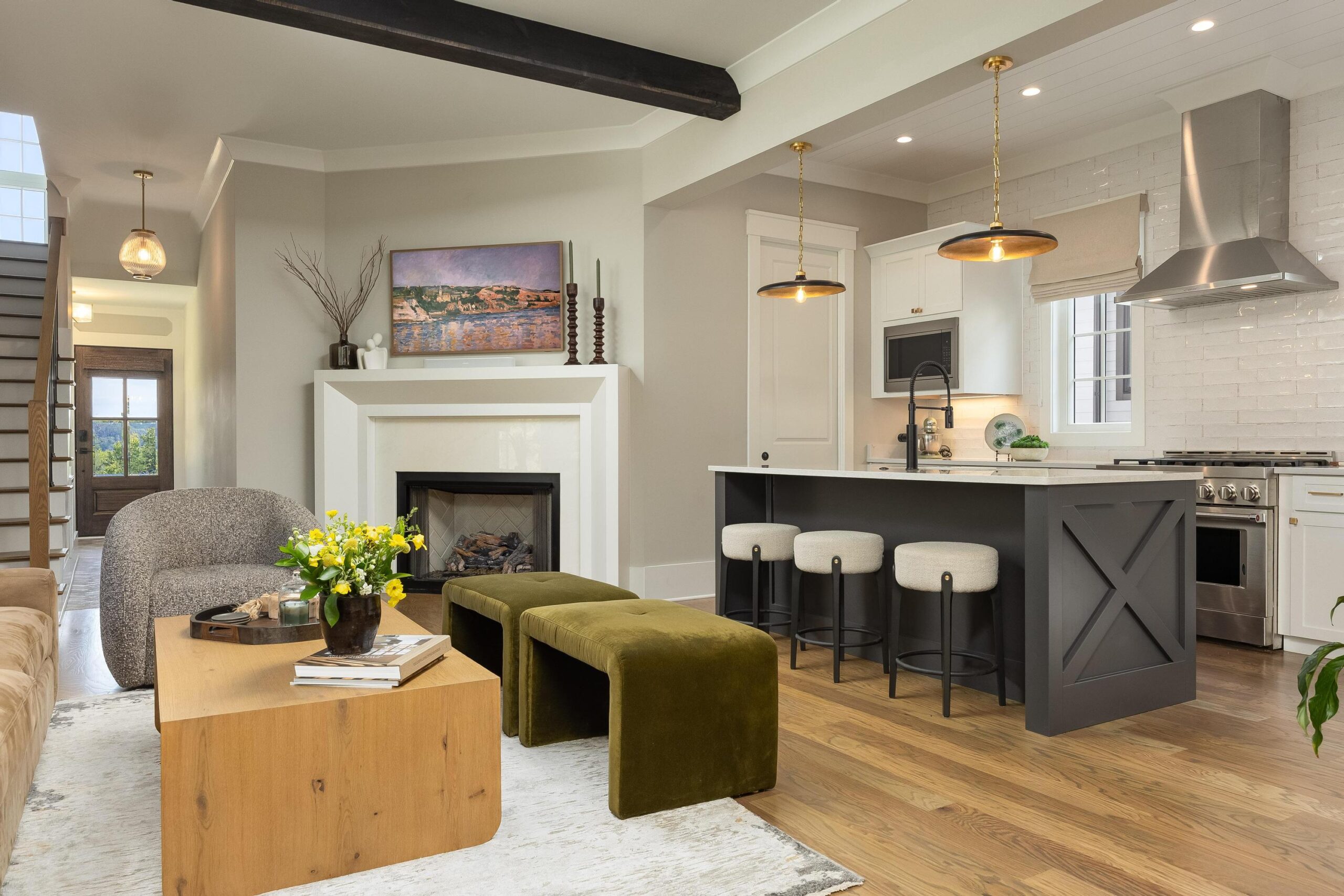 Modern open-concept living room and kitchen with wood floors, a fireplace, a kitchen island with stools, and neutral-toned furniture—perfect for comfortable generational gatherings.